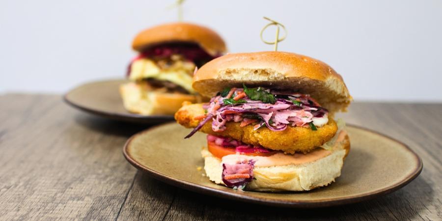 An image of two chicken burgers with filling on two separate plates.